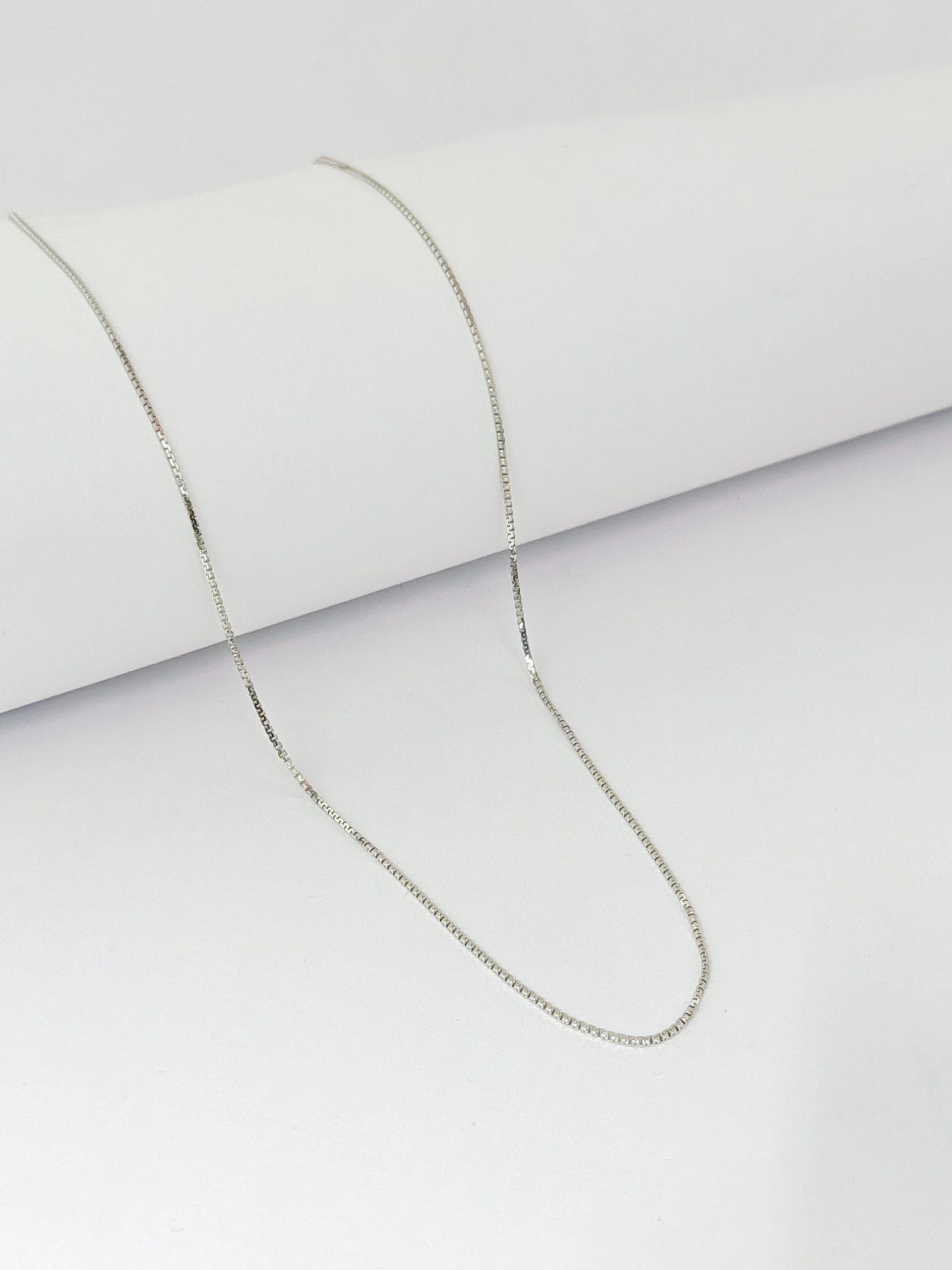 Silver chain necklace on a light gray background